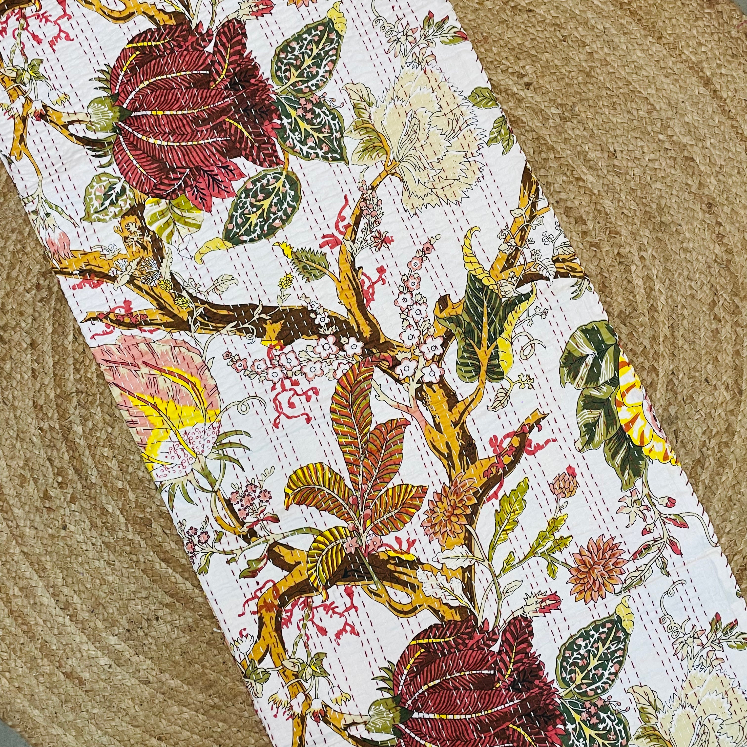 Close-up of a floral-patterned fabric with red roses and green leaves on a textured surface.