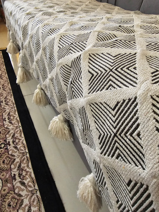Textured fabric with geometric pattern and tassels on a neutral background