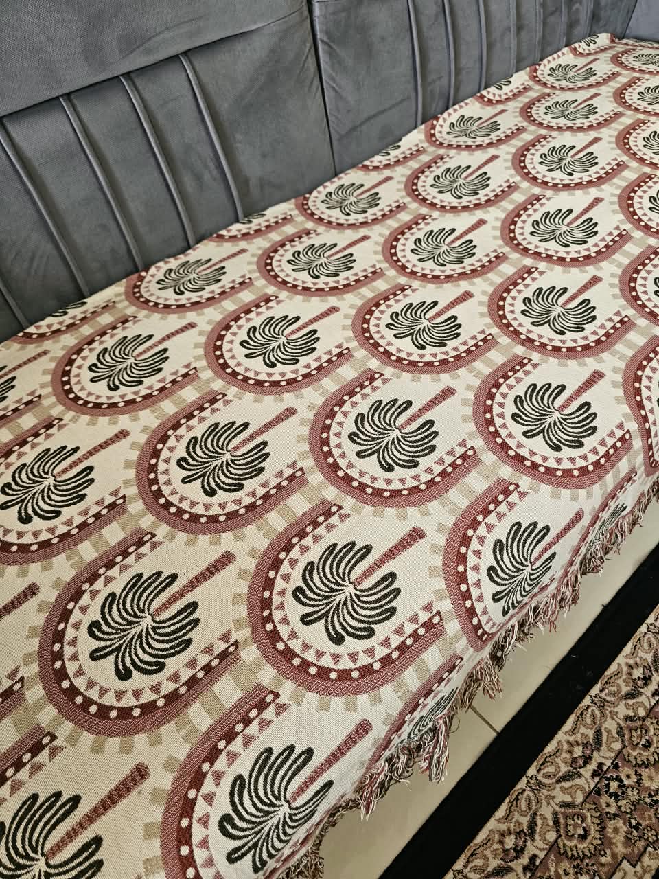 Vasaca handwoven jacquard cotton sofa cover featuring an arch and palm tree pattern with tassels on a grey sofa.