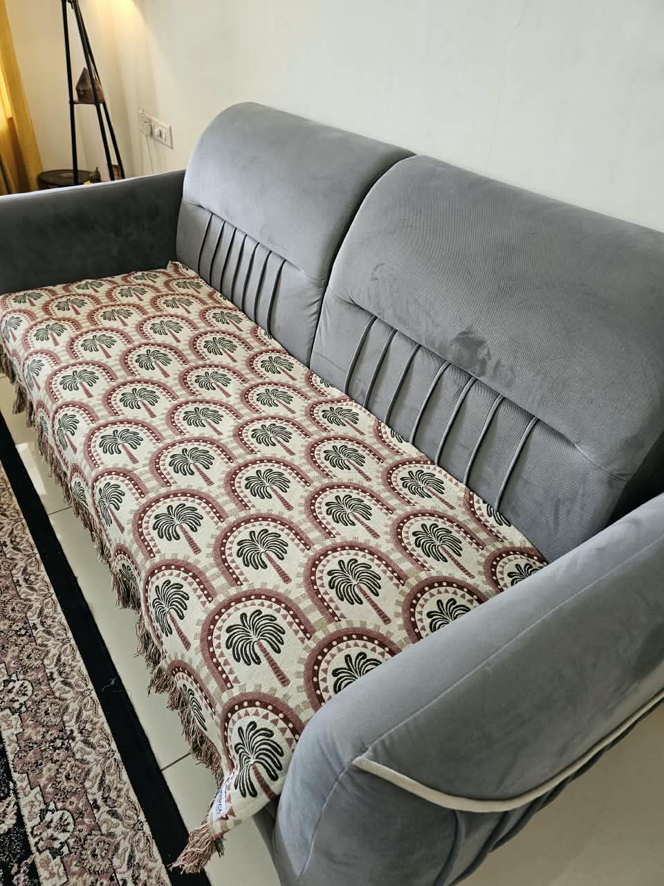 Vasaca handwoven jacquard cotton sofa cover featuring an arch and palm tree pattern with tassels on a grey sofa.