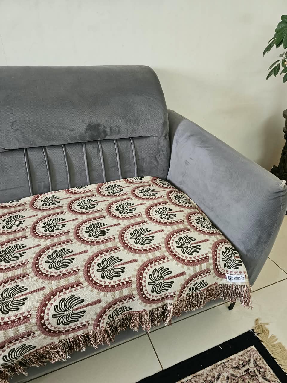 Vasaca handwoven jacquard cotton sofa cover featuring an arch and palm tree pattern with tassels on a grey sofa.