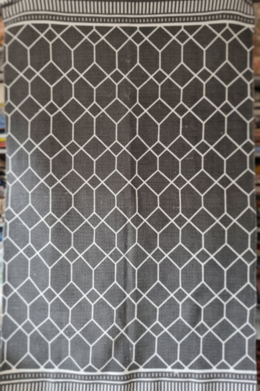 Vasaca charcoal dark grey handwoven cotton flatweave runner rug with off-white geometric lattice pattern, striped end-borders, and tassels.