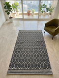 Vasaca charcoal dark grey handwoven cotton flatweave runner rug with off-white geometric lattice pattern, striped end-borders, and tassels.