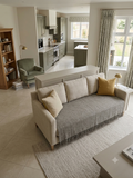 Vasaca dark grey thick handwoven cotton seat-only sofa runner with slubbed texture and fringed edge, fitted onto the seating cushions of a three-seater sofa.