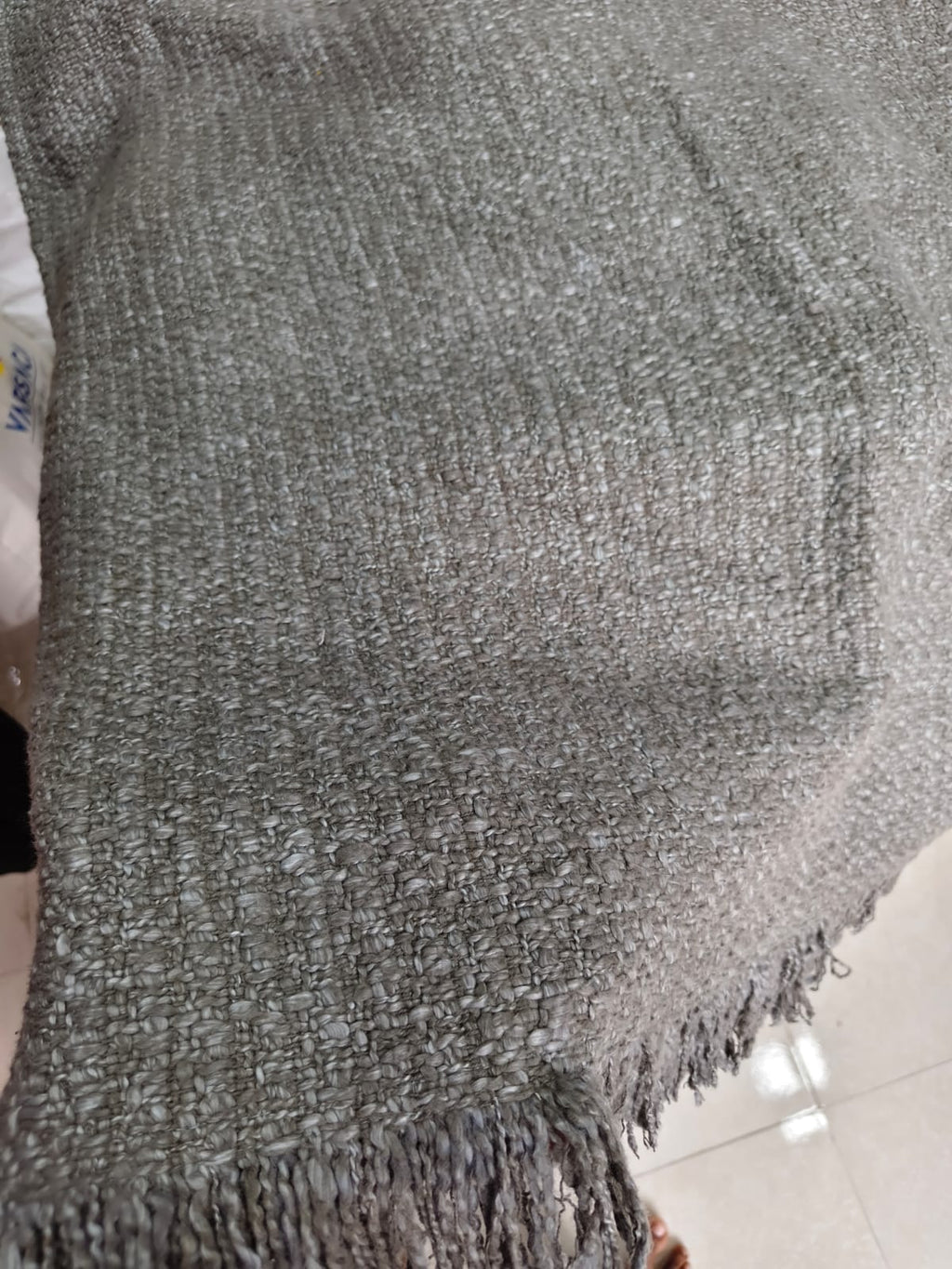 Vasaca dark grey thick handwoven cotton seat-only sofa runner with slubbed texture and fringed edge, fitted onto the seating cushions of a three-seater sofa.