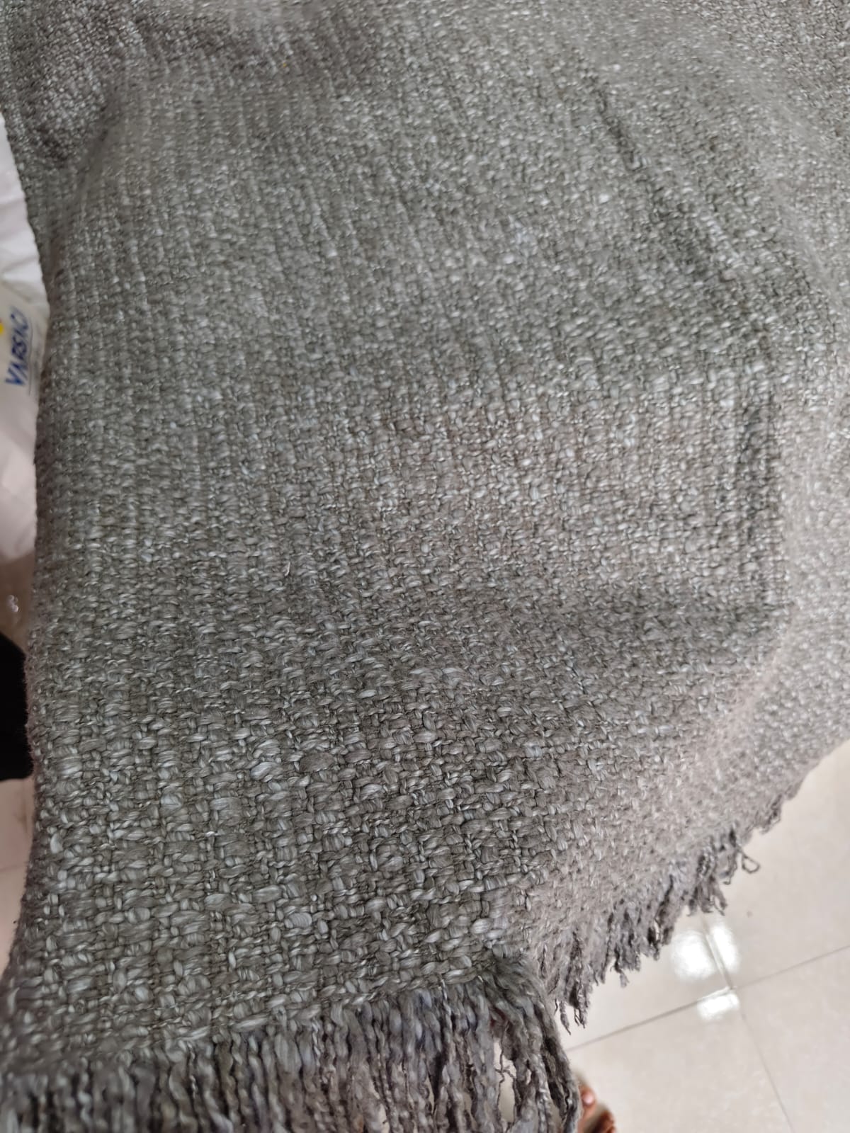 Vasaca dark grey thick handwoven cotton seat-only sofa runner with slubbed texture and fringed edge, fitted onto the seating cushions of a three-seater sofa.