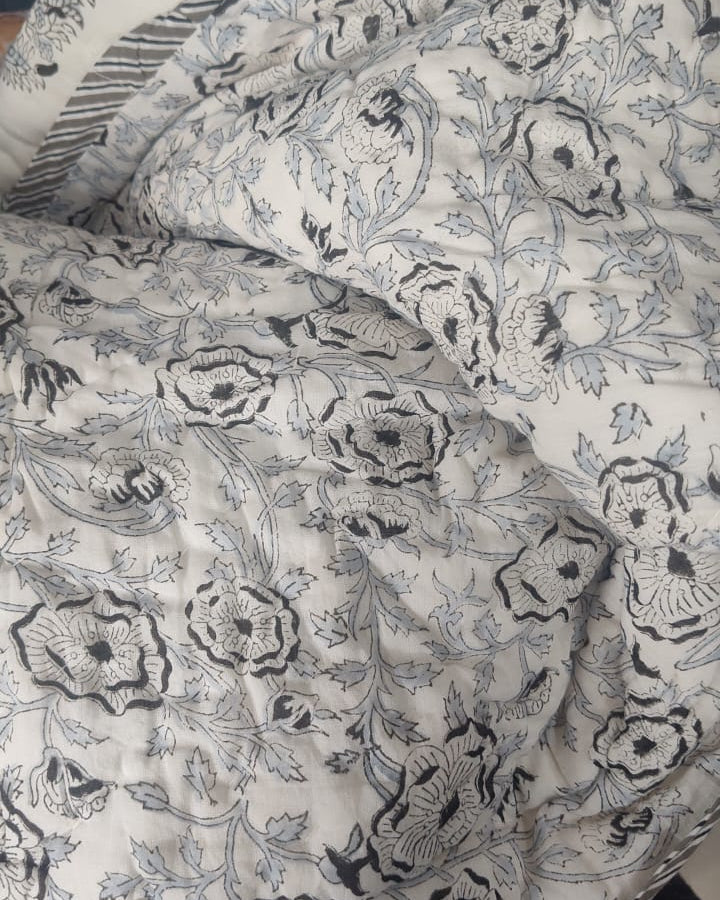Close-up view of a Vasaca handblock printed cotton single bed razai featuring traditional charcoal floral motifs on a cream fabric with quilted texture.