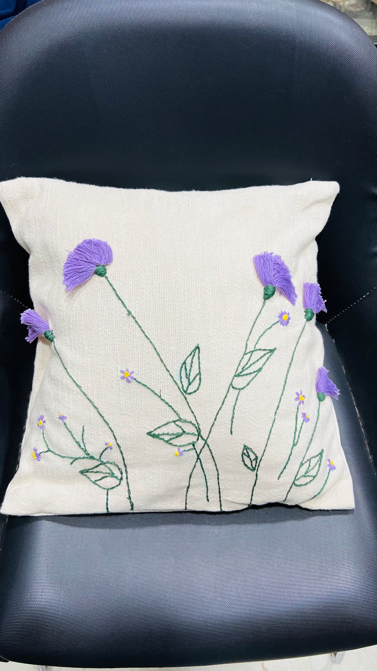 Vasaca jute-cotton handcrafted floral embroidered throw pillow cover featuring hand-stitched green stems and textured purple floral blooms on a natural off-white jute-cotton base