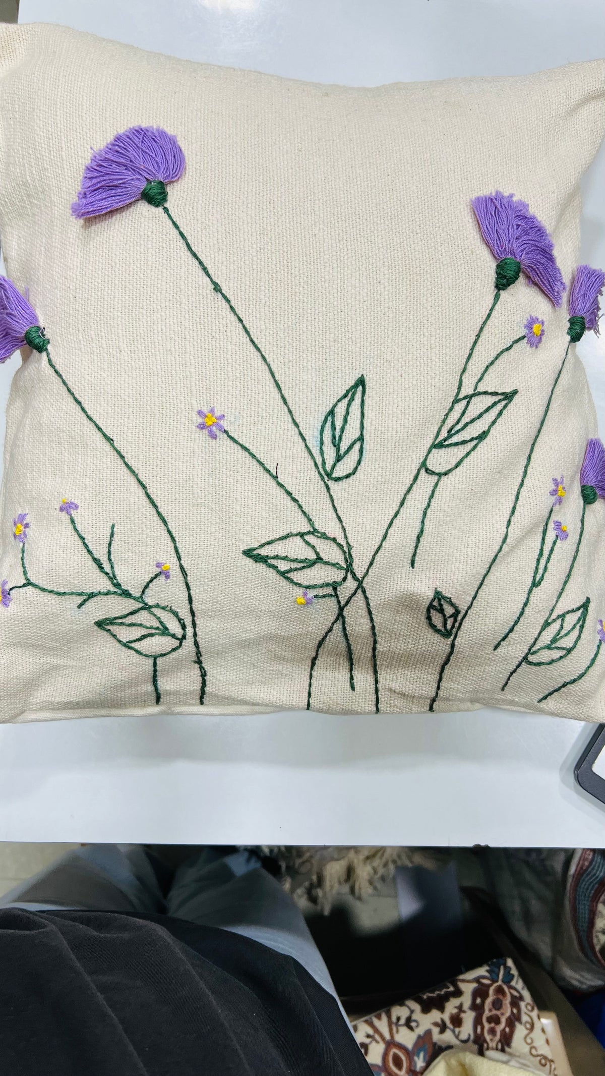 Vasaca jute-cotton handcrafted floral embroidered throw pillow cover featuring hand-stitched green stems and textured purple floral blooms on a natural off-white jute-cotton base