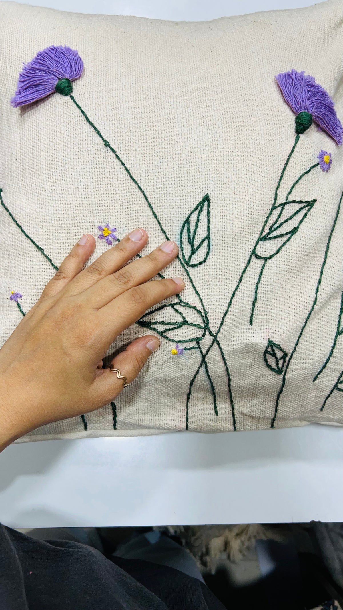 Vasaca jute-cotton handcrafted floral embroidered throw pillow cover featuring hand-stitched green stems and textured purple floral blooms on a natural off-white jute-cotton base.