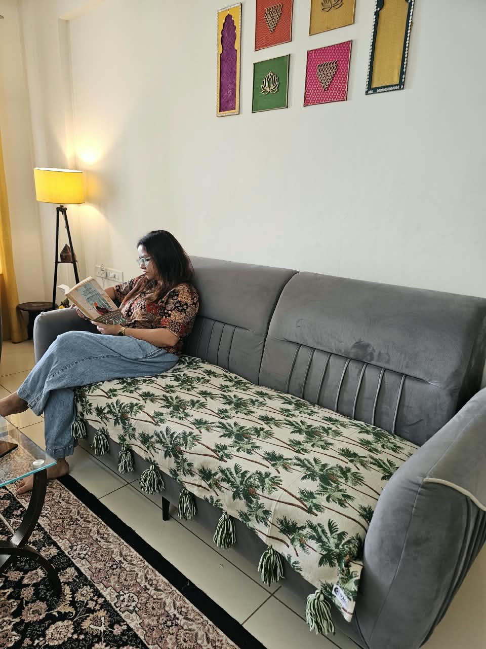 Vasaca handwoven cotton sofa runner featuring a green tropical palm tree pattern and decorative tassels on a grey sofa.