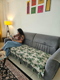 Vasaca handwoven cotton sofa runner featuring a green tropical palm tree pattern and decorative tassels on a grey sofa.