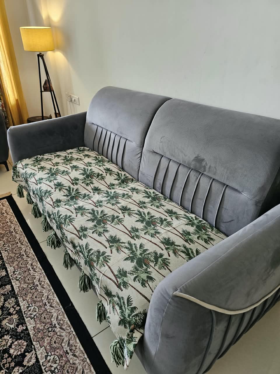 Vasaca handwoven cotton sofa runner featuring a green tropical palm tree pattern and decorative tassels on a grey sofa.