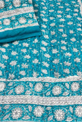 Close-up view of a Vasaca handblock printed cotton single bed razai featuring a vibrant turquoise blue background with white lotus floral patterns and bordered edges.
