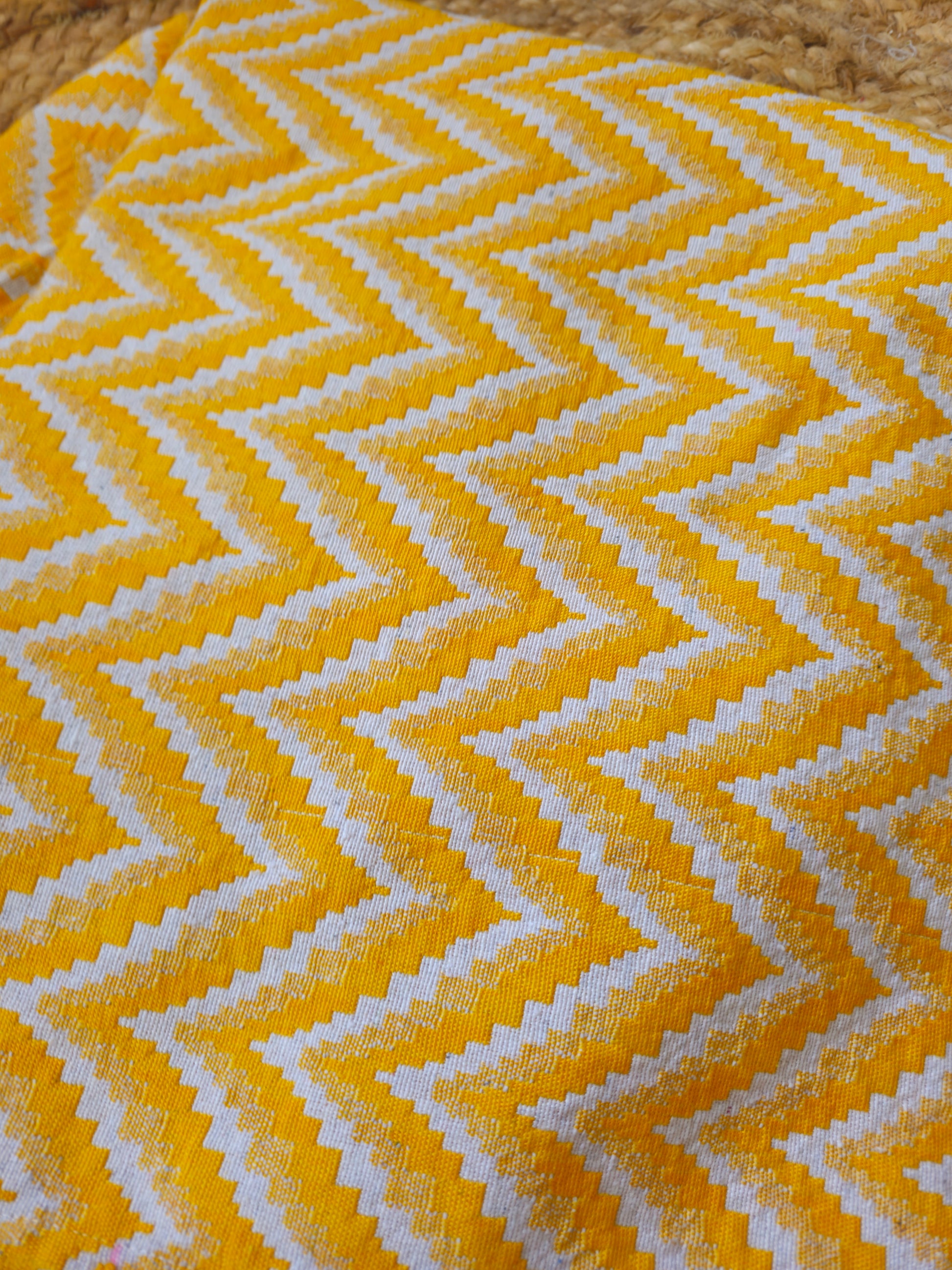 Yellow and white zigzag patterned fabric on a wooden surface
