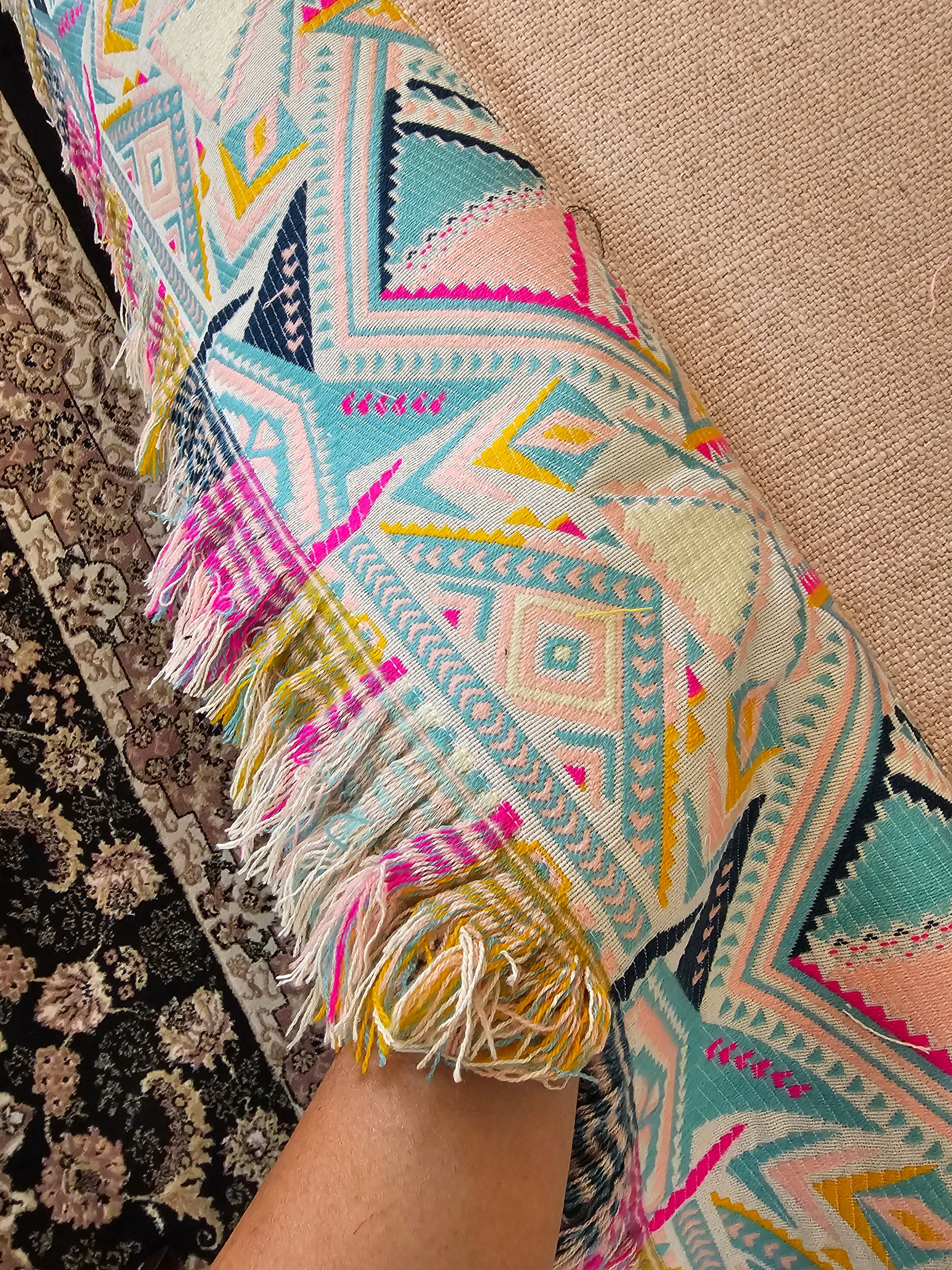 Colorful patterned fabric with tassels on a textured surface