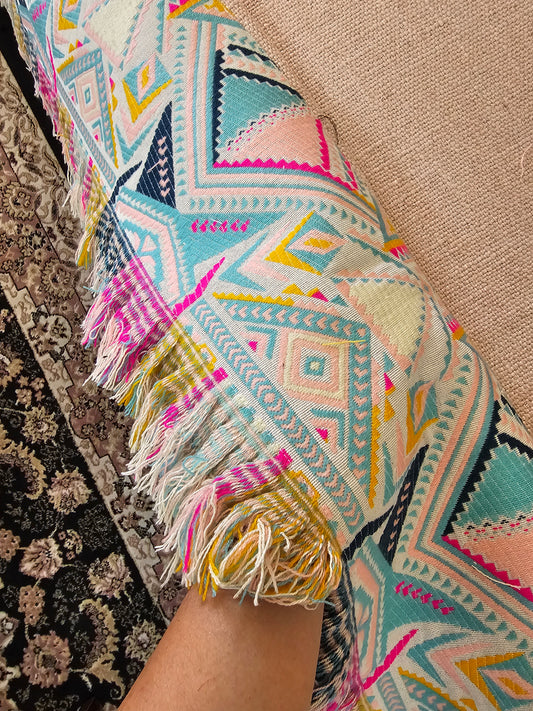 Colorful patterned fabric with tassels on a textured surface