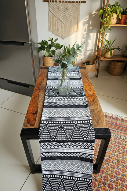 Black and white patterned table runner on a wooden chair with a colorful rug in the background.