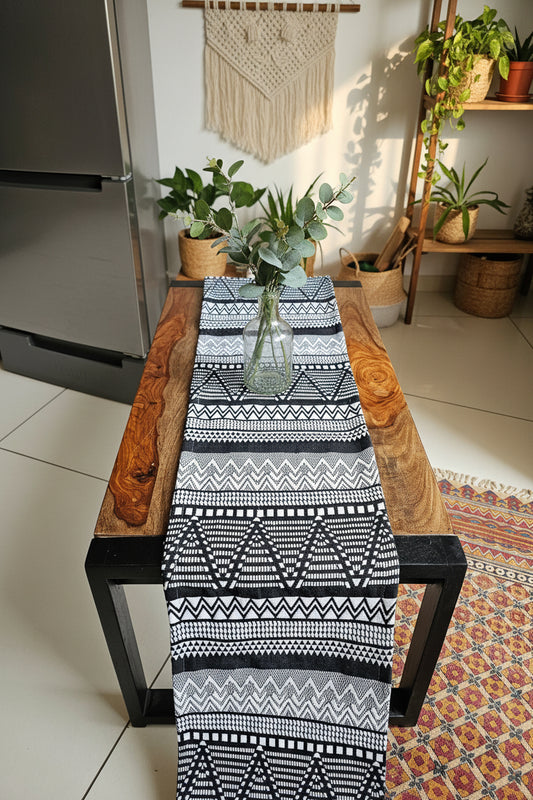 Black and white patterned table runner on a wooden chair with a colorful rug in the background.