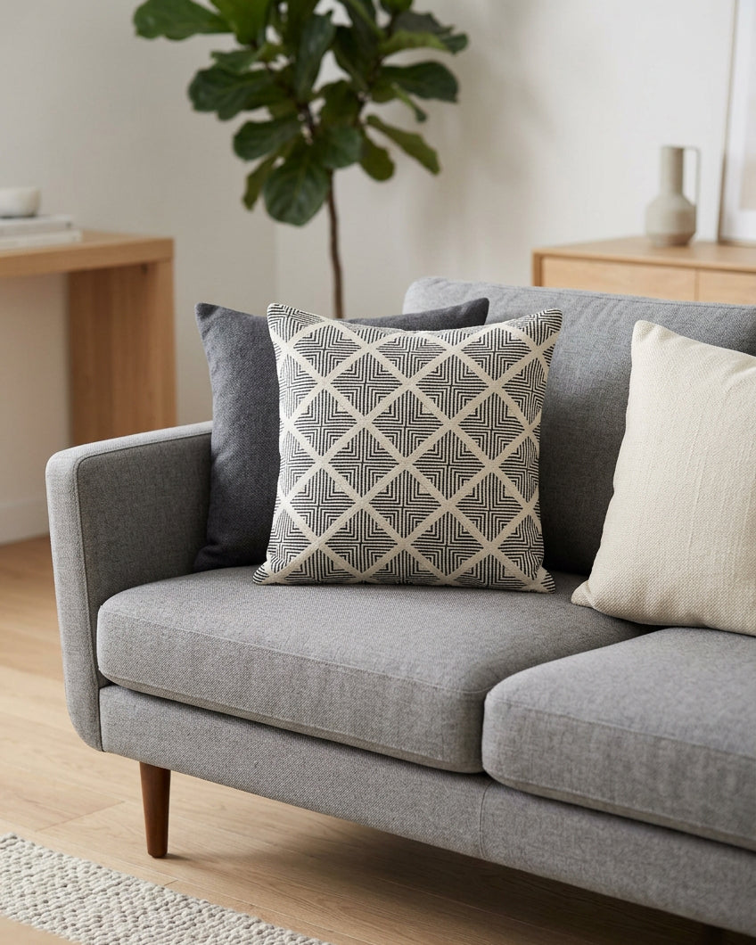 Square off-white cotton cushion cover with a charcoal black geometric diamond line pattern displayed flat.