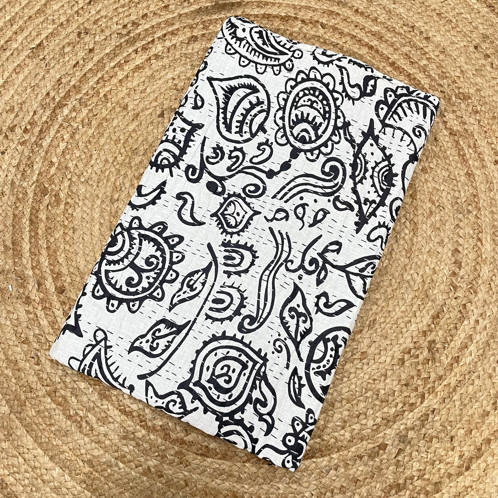 Black paisley patterned fabric on a textured beige background
