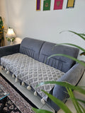 Gray sofa with a patterned cushion in a room with a white wall and decorative items.