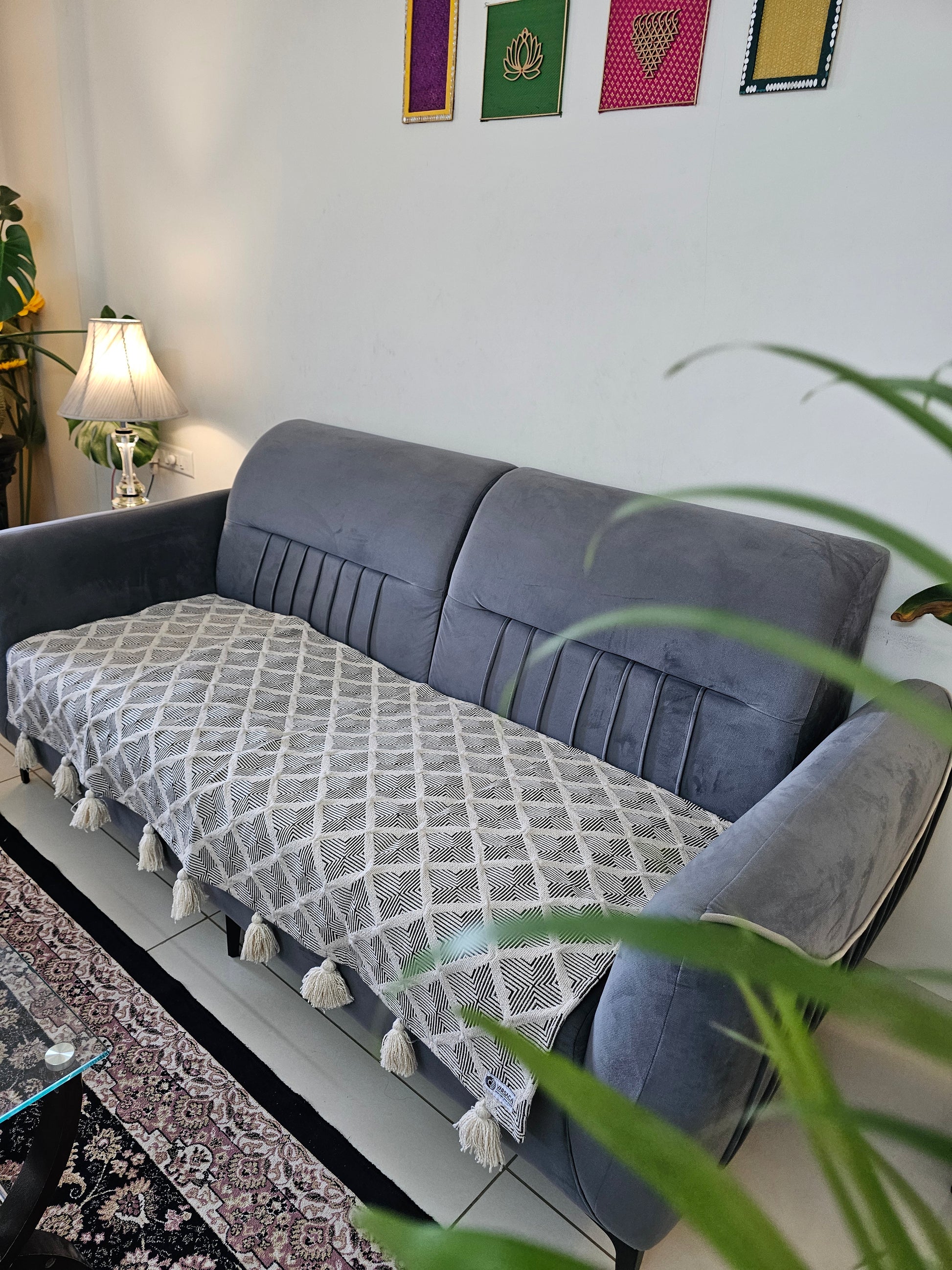 Gray sofa with a patterned cushion in a room with a white wall and decorative items.