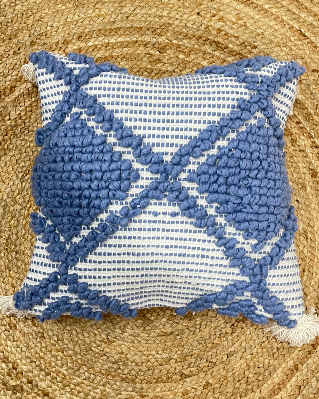 Set of 5 coastal boho-style cotton cushion covers, featuring two end pillows with blue tufted diamonds, two inner pillows with textured blue patterns, and a central white pillow with blue tufted lines and tassels, arranged neatly on a blue sofa in a bright living room.