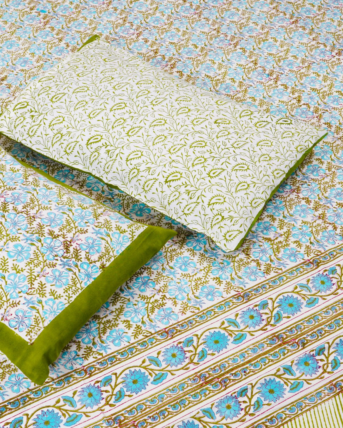 Folded 100x108 inch king size cotton bedsheet and matching pillow covers featuring a traditional blue and olive-green handblock floral and vine print.