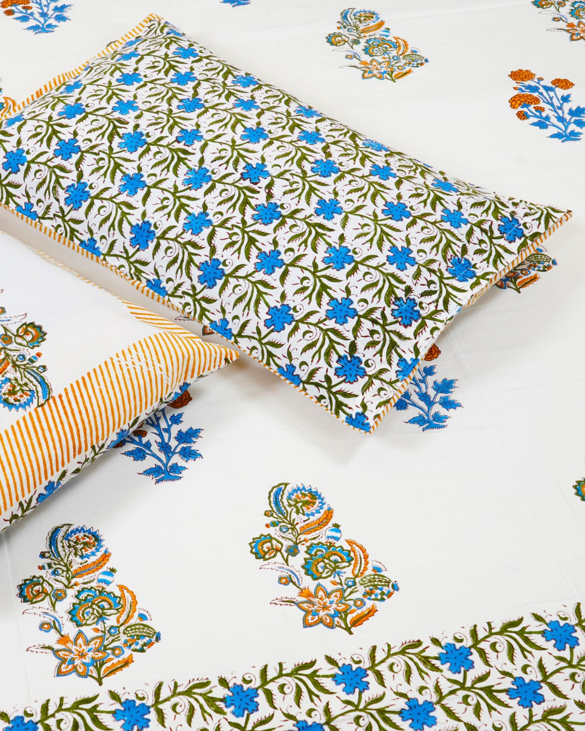 100x108 inch king size cotton bedsheet and matching striped pillow covers styled with a traditional blue floral butta and orange motif handblock print.