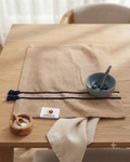 Natural textured burlap-style cotton placemat featuring navy blue horizontal stripes and side tassels.