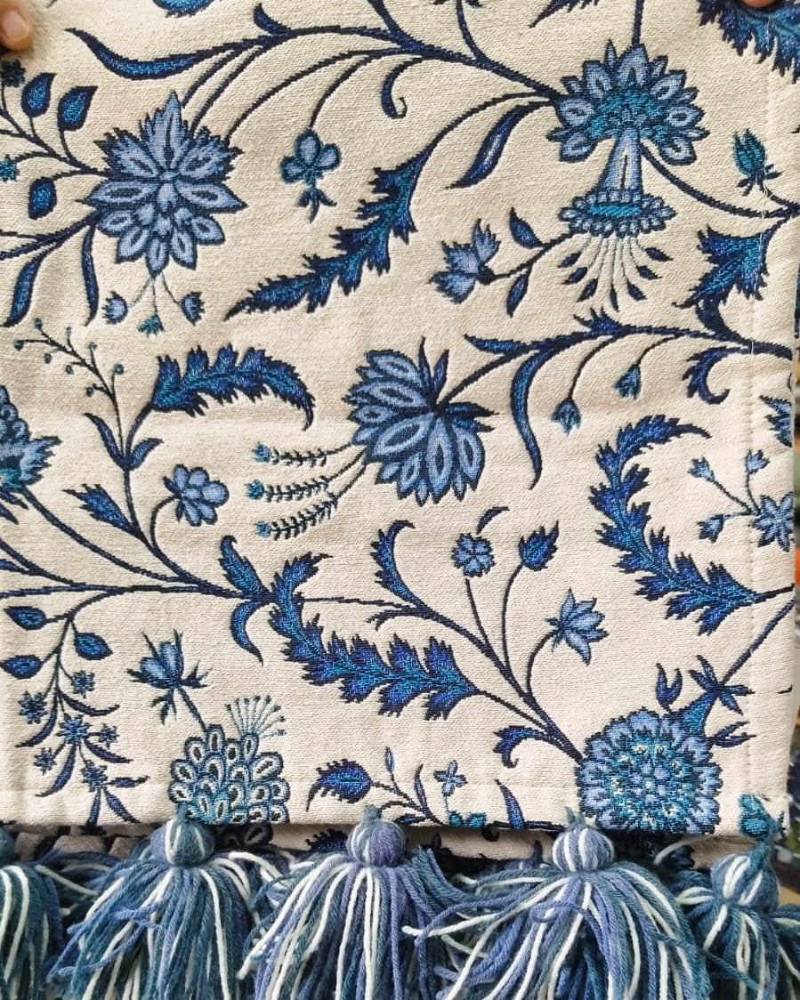 Blue and white floral Jacquard cotton dining table runner featuring an intricate botanical vine pattern and two-tone woolen hanging tassels, with Vasaca brand labels.