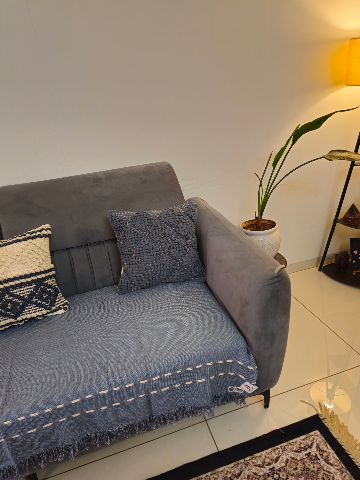 Gray sofa with a blue throw blanket and patterned pillow in a living room setting.