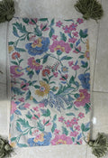 Rectangular boho-style cotton cushion cover featuring a vintage botanical floral pattern in pink, blue, and yellow, complete with sage-green corner tassels, laid flat on a light surface.