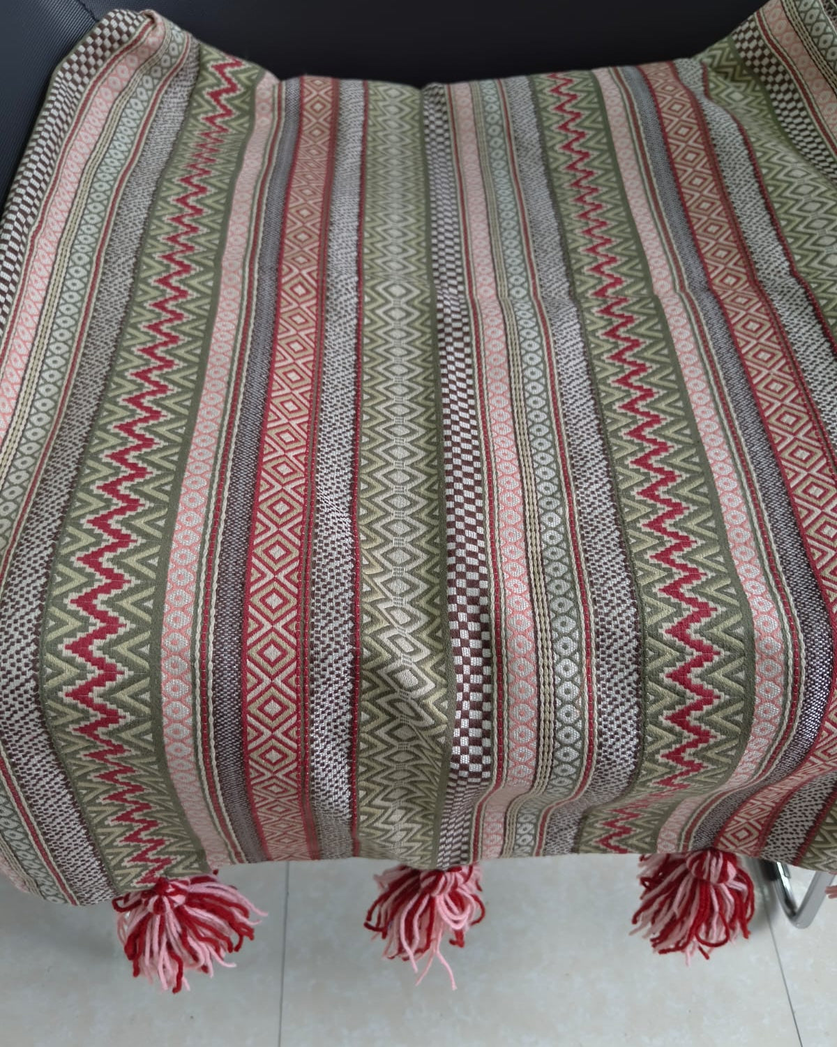 Boho striped Jacquard cotton sofa throw cover featuring geometric diamond and chevron patterns in olive green and rust red with pink tassel details.