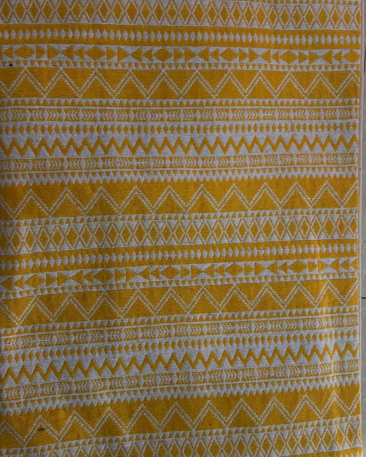 Rectangular boho-style cotton cushion cover featuring a geometric zigzag pattern in mustard yellow and white, complete with yellow-and-white corner tassels and white center tassels, laid flat on a light surface.