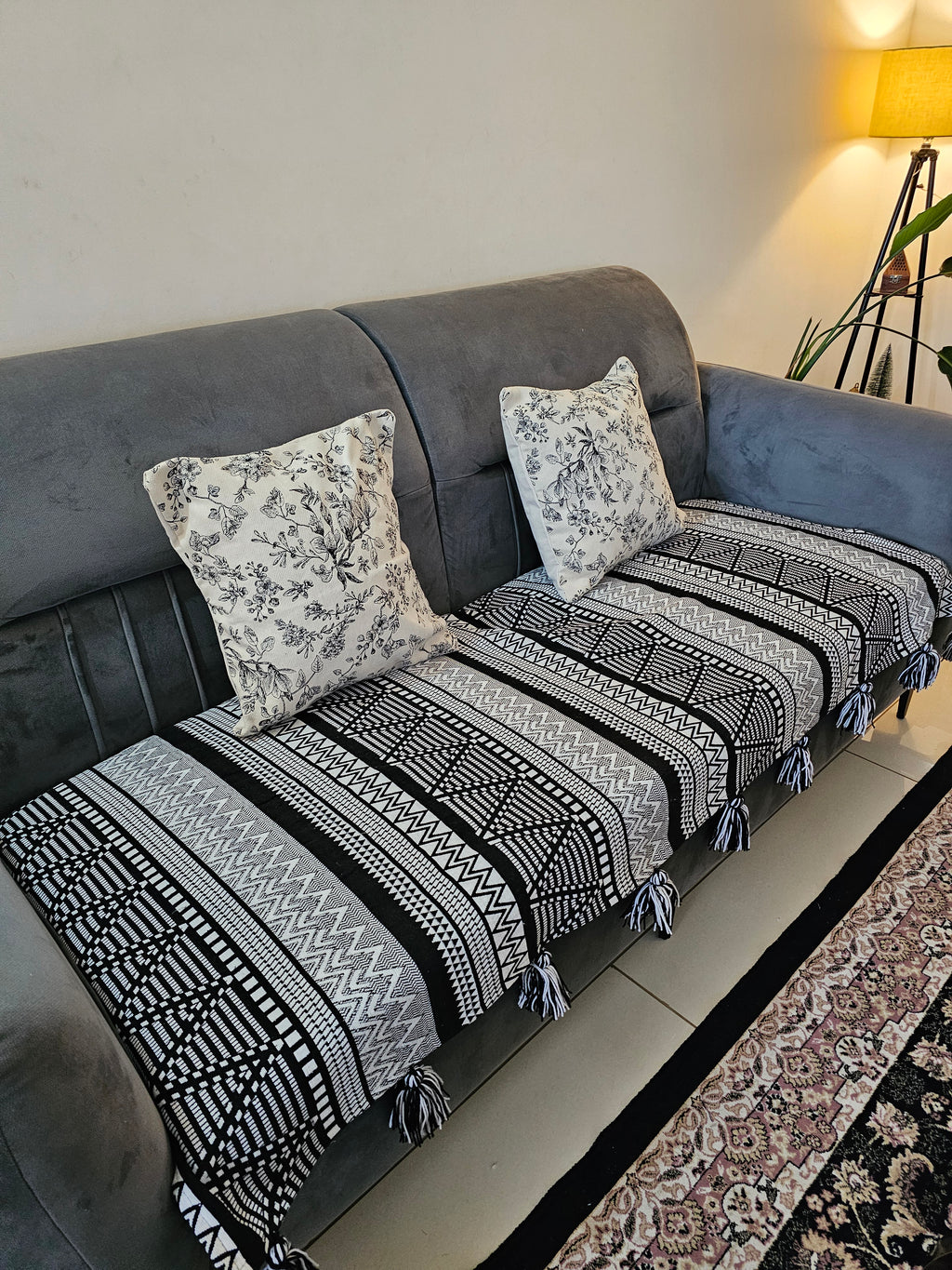 Gray sofa with patterned black and white throw blanket and pillows.
