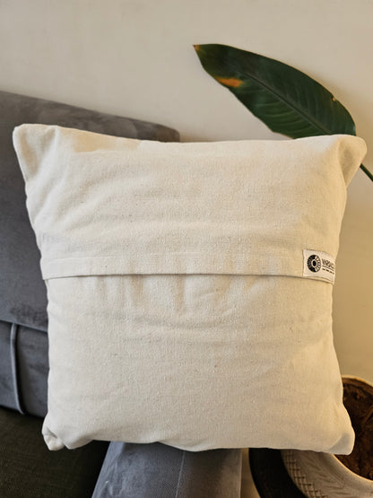 Beige pillow with a brand tag on a gray surface