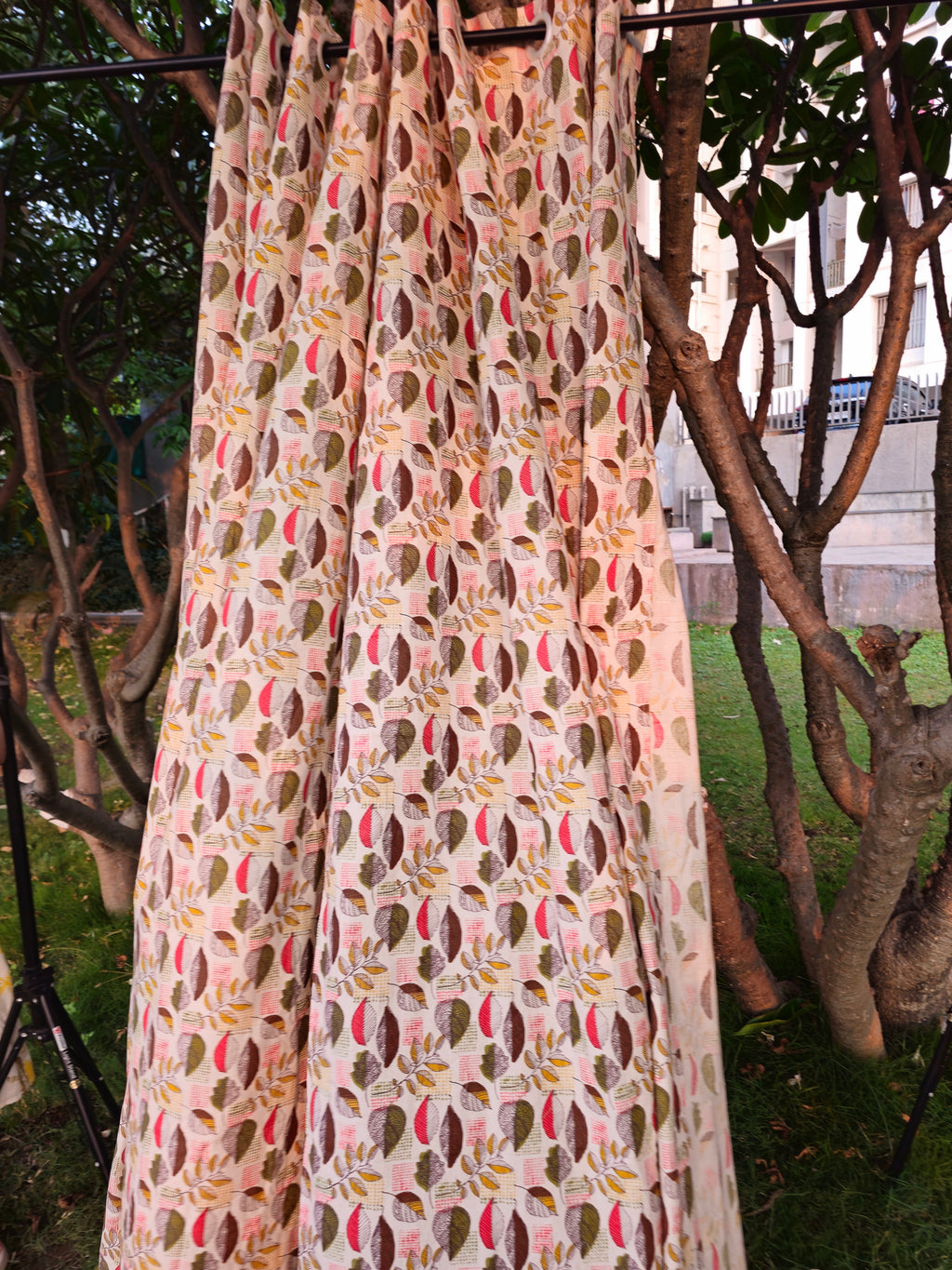 Long floral-patterned fabric hanging outdoors with trees and a building in the background