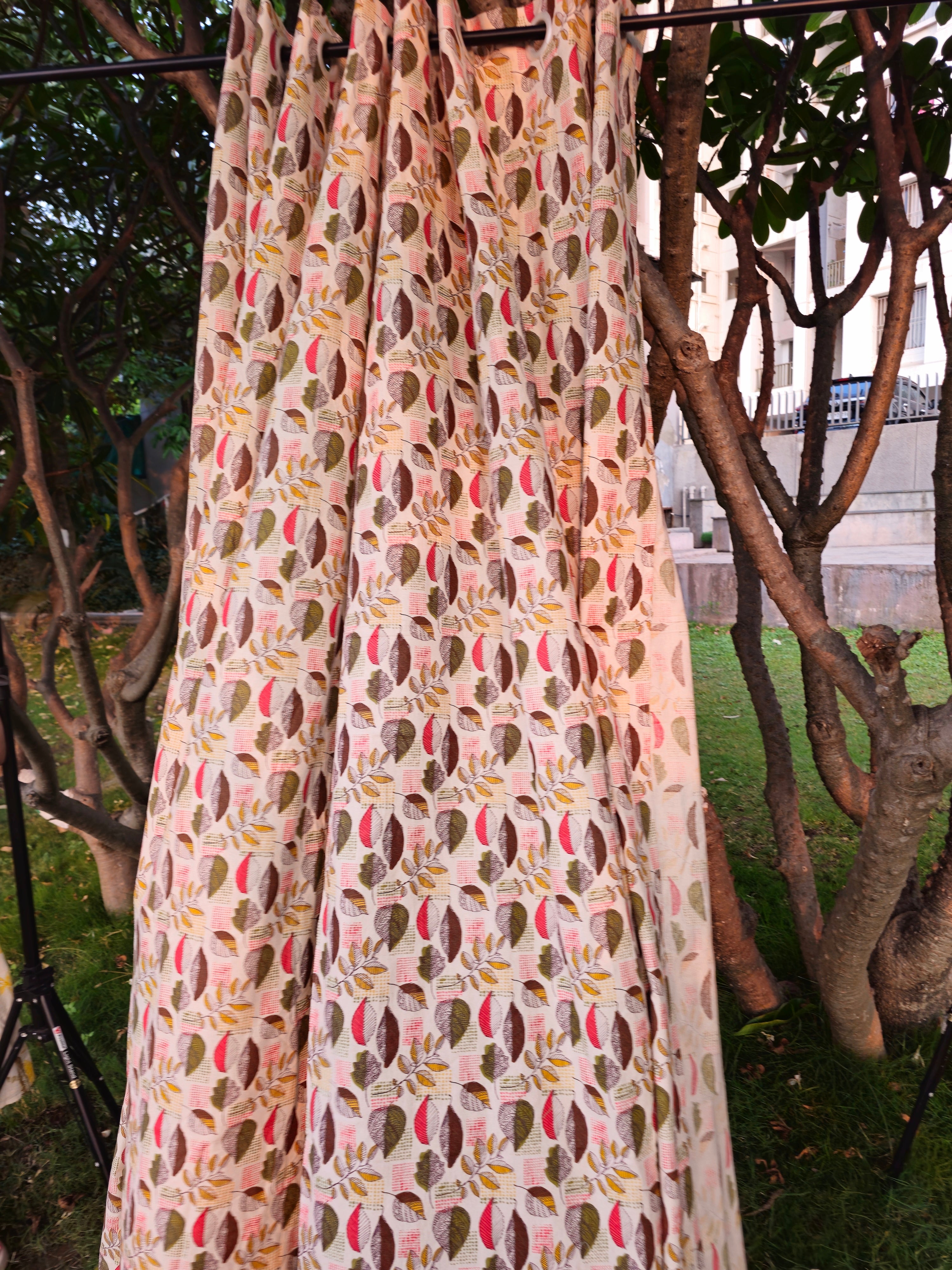 Long floral-patterned fabric hanging outdoors with trees and a building in the background