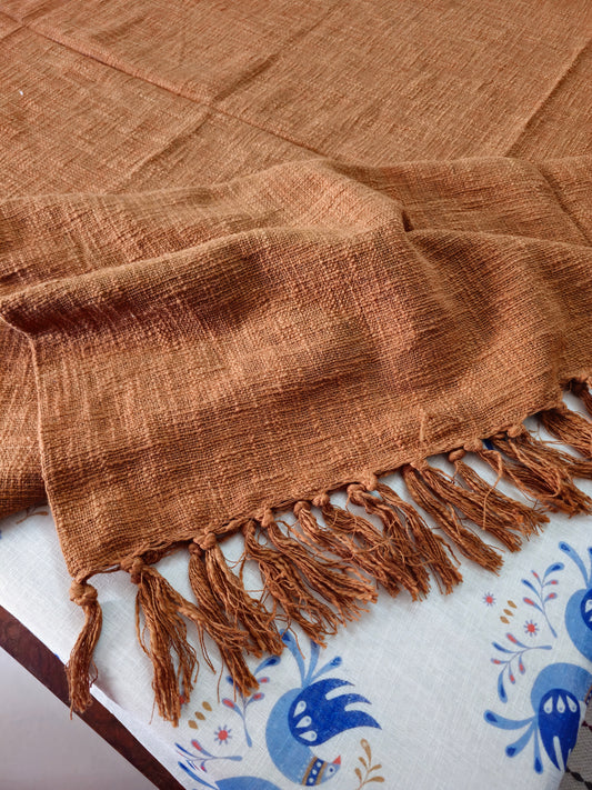 Brown woven blanket with fringes on a white surface with blue patterns