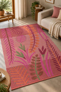 Close-up of a coral botanical handwoven cotton tufted rug featuring rich textured tropical leaf and foliage patterns in green, orange, and pink.