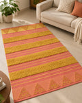 Coral and mustard handwoven cotton tufted rug featuring raised geometric triangle motifs and plush textured stripes in a modern living room setup.