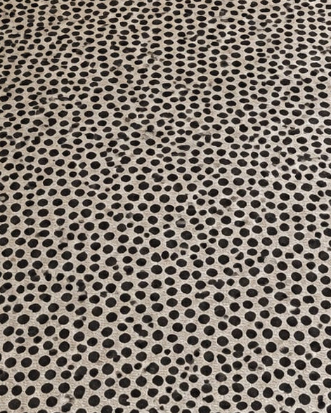 Off-white cotton area rug with an all-over charcoal black polka dot pattern styled in a warm, modern living room setup.