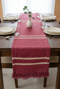 Dark pink jute-cotton handloom table runner featuring two parallel rows of off-white crochet lace trim and a matching self-fringed hem, with Vasaca brand labels.