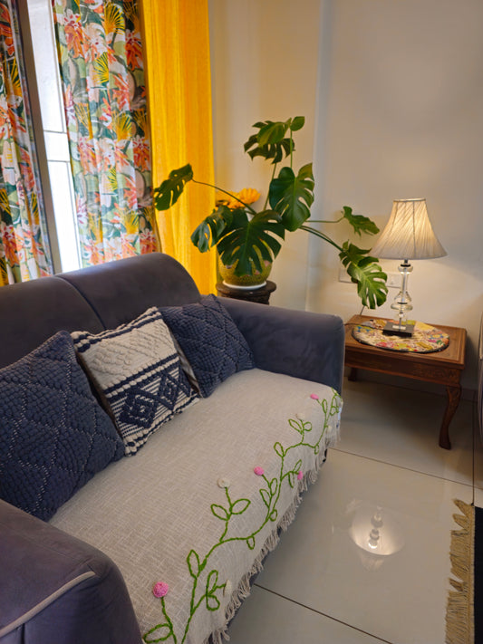 Living room with a gray sofa, decorative pillows, and a small table with a lamp.