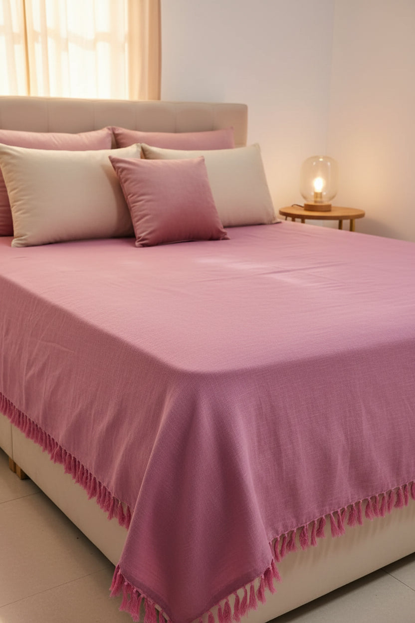 Dusty rose handloom slub cotton king size bed cover featuring a textured solid weave and handcrafted fringe tassels.