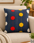 Square slate-blue cotton cushion cover featuring colorful applique circles in red, yellow, and white, accented with traditional hand-embroidered kantha stitching.