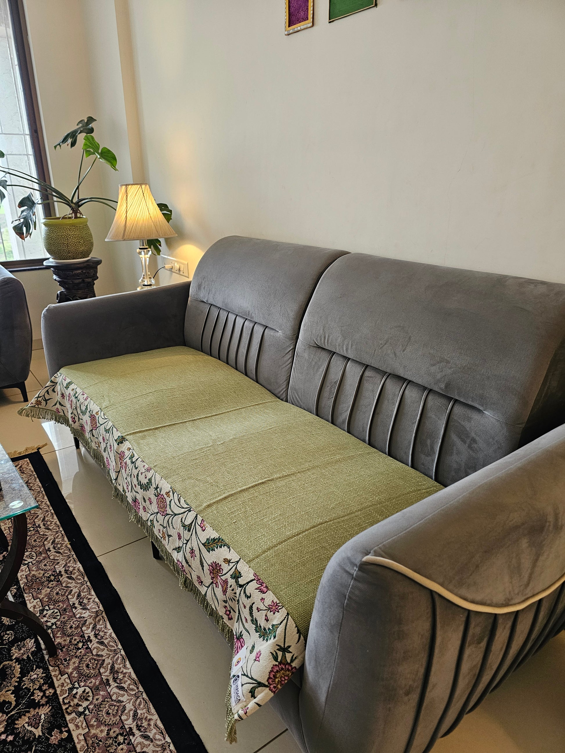 Gray sofa with a floral-patterned throw blanket in a living room setting.