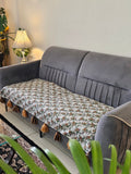 Gray sofa with a patterned cushion and decorative items on a shelf.